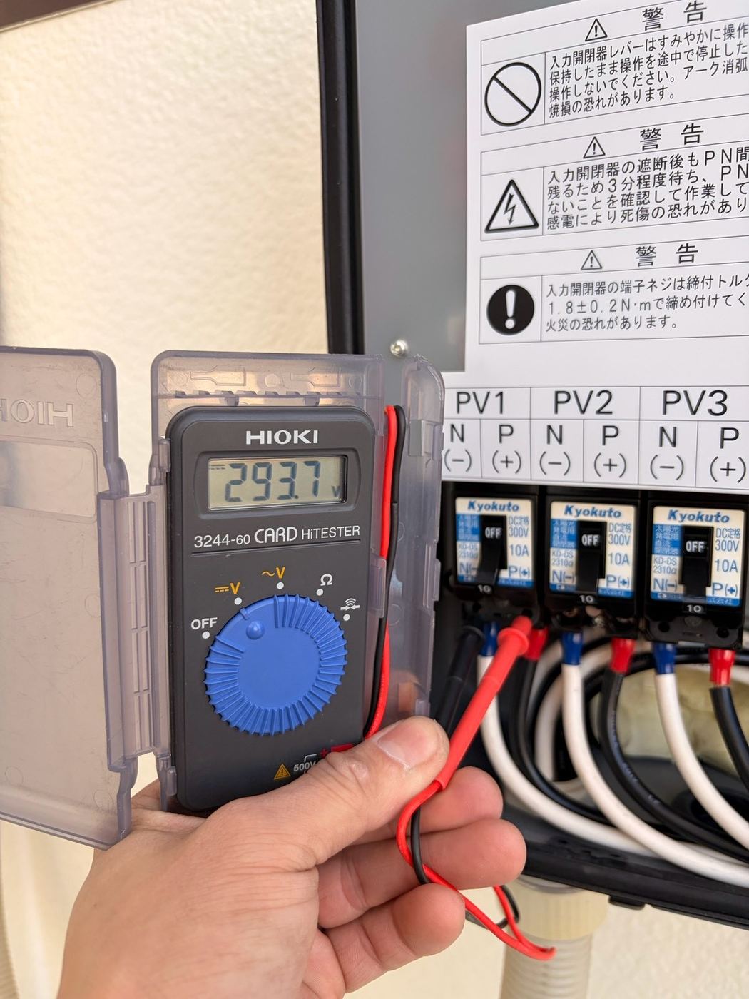 接続箱でPV系統ごとの電圧を測定している様子